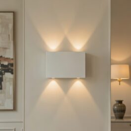 Modern white rectangular rechargeable LED wall sconce with up and down lighting effect on a beige wall.